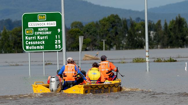 SES volunteers ferry stranded people from Gillieston Heights to Maitland across a flooded Cessnock Road.