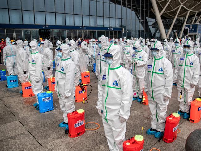 TOPSHOT - Staff members line up at attention as they prepare to spray disinfectant at Wuhan Railway Station in Wuhan in China's central Hubei province on March 24, 2020. - China announced on March 24 that a lockdown would be lifted on more than 50 million people in central Hubei province where the COVID-19 coronavirus first emerged late last year. (Photo by STR / AFP) / China OUT