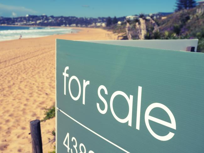 Real estate for sale sign on a beach with waves