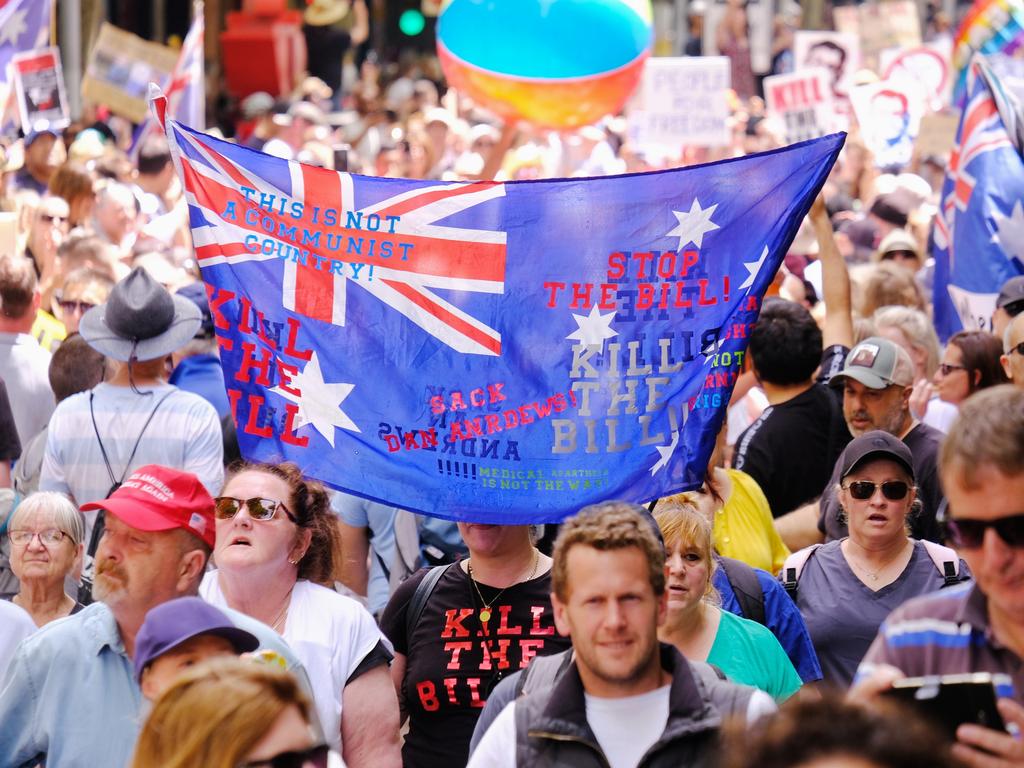 A man waves an Australian flag with anti-Daniel Andrews slogans on it. Picture: NCA NewsWire / Luis Ascui