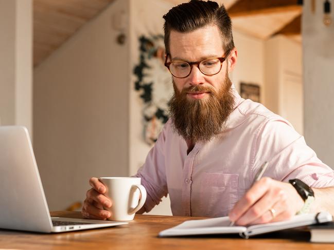 A man sitting at home, using his laptop to search for a new job.