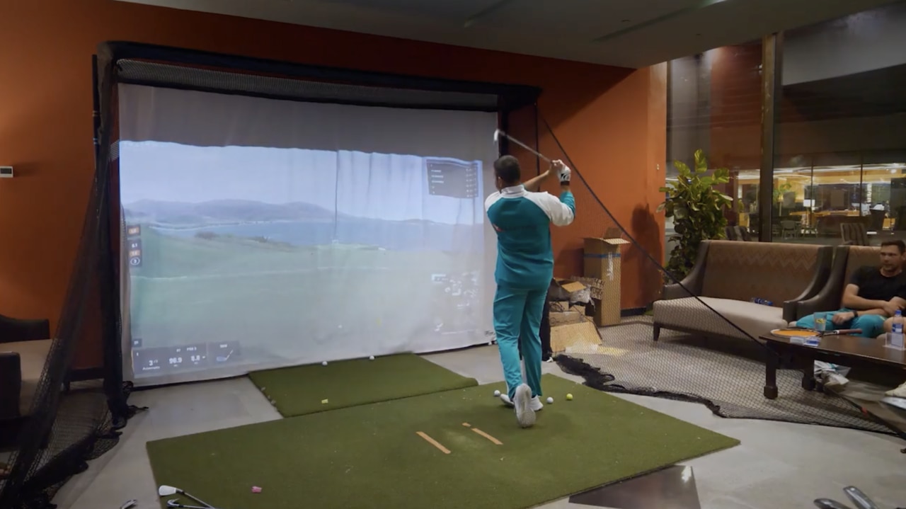 Usman Khawaja tees off on the golf simulator in the team hotel on the tour of Pakistan. Photo: Amazon Prime Video