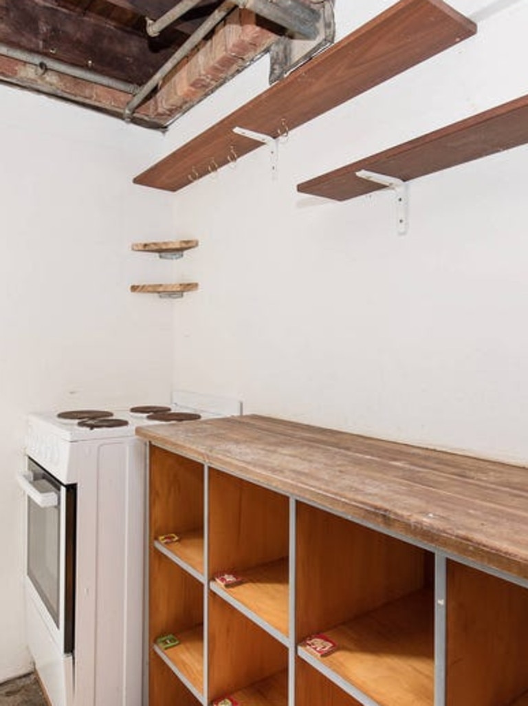 The kitchen space, featuring an alleged gas cooktop, and an exposed ceiling.