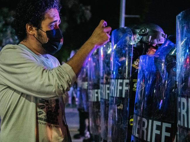 A demonstrator attempts to interview police officers. Picture: Getty Images/AFP