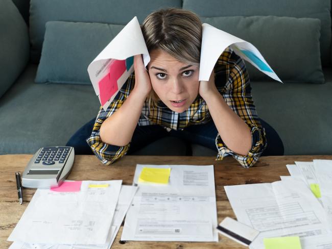 Portrait of worried and desperate young woman feeling stressed while working through finances. Sitting on the sofa making anxious gestures. In paying debts and bills and financial problems concept.