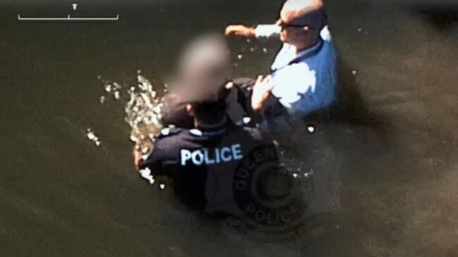 The man is met by police officers in the water.