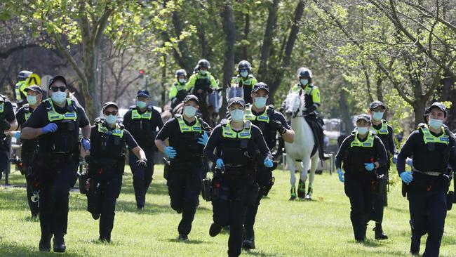 Police officers charge towards anti-vax protesters. Picture: David Crosling