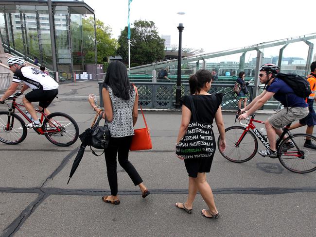 Pedestrians navigate cyclists to cross the pedestrian bridge at Darling Harbour.