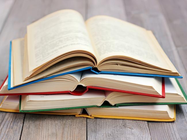 Four open books in the colored cover on the table made of boards.A stack of books in the colored covers on the table with a red tablecloth. Still life with books. iStock image