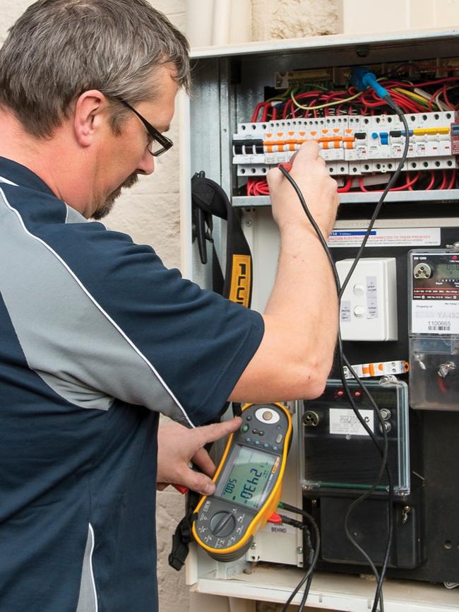 A Sharpe Services electrician checking and testing the safety of a residential electrical switchboard in 2018.