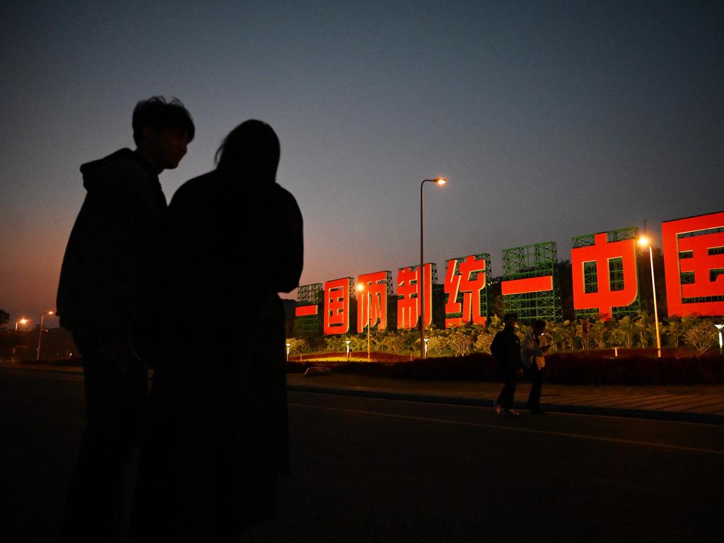 TOPSHOT - A couple stands near a giant propaganda slogan which reads 