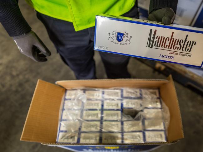 An Australian Border Force officer in front of a shipping container full of illegally imported cigarettes. Picture: Jake Nowakowski