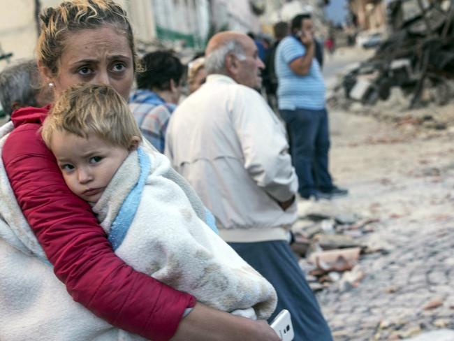 A woman holds a child as they stand in the street following the huge quake that could be felt in Rome. Massimo Percossi/ANSA