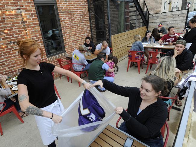 “Save on toilet paper” ... Hersh’s Pizza bartender Abby Hopper collects a Ray Rice Baltimore Ravens football jersey from Erin McGonigle. Picture: Steve Ruark