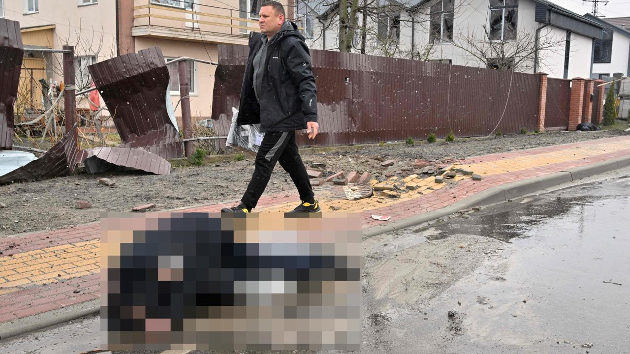 A man walks past the body of a civilian in Bucha. Picture: Sergei Supinsky/AFP