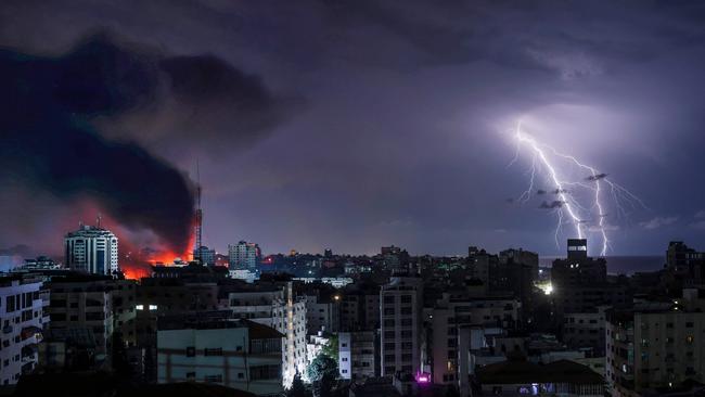 Lightning strikes as smoke billows following Israeli bombardment of Gaza City. Picture: Mohammed Abed/AFP