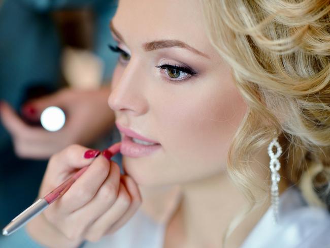 Wedding makeup artist making a make up for bride. Beautiful sexy model girl indoors. Beauty woman with curly hair. Female portrait. Bridal morning of a cute lady. Close-up hands near face. Picture: iSTOCK