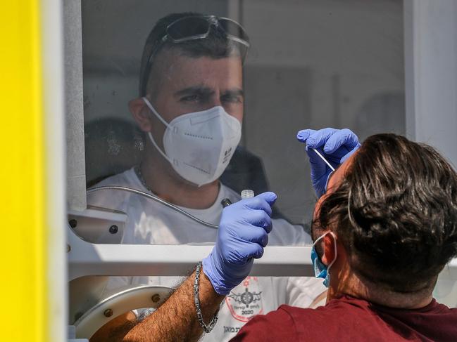 A paramedic of the Magen David Adom, Israel's national emergency, collects a swab sample from a Palestinian man at a mobile testing station. Picture: AFP.