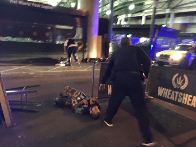 Armed police stand over one of the attackers, shot dead. Picture: AFP