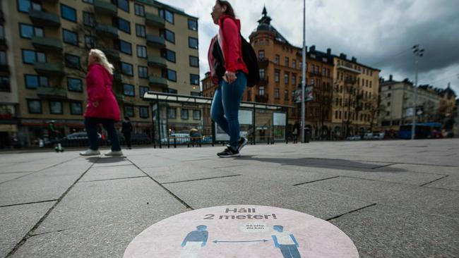 A big sticker of the healthcare services of Sweden is placed on a pavement in the heart of Stockholm recommending people follow the two-metre distance rule. Picture: Jonathan Nackstrand/AFP