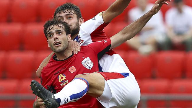 Adelaide United’s Nikola Mileusnic (front) and Newcastle’s Ivan Vujica compete for the ball on Saturday night.