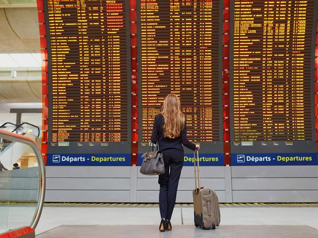 ESCAPE: AIRPORT STORIES, GABBI JOHNSTON - Young elegant business woman with hand luggage in international airport terminal, looking at information board, checking her flight. Cabin crew member with suitcase. Picture: Istock
