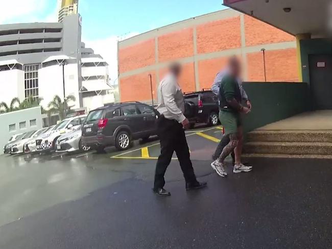 Garry James Brush (in green) is walked into the Southport Watchhouse by detectives in 2021. Picture: Queensland Police Service