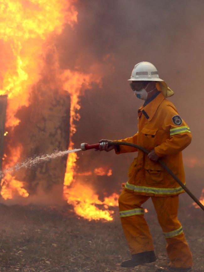 A firefighter holds back a fire at Tinonee near Taree. Pictures: Nathan Edwards.