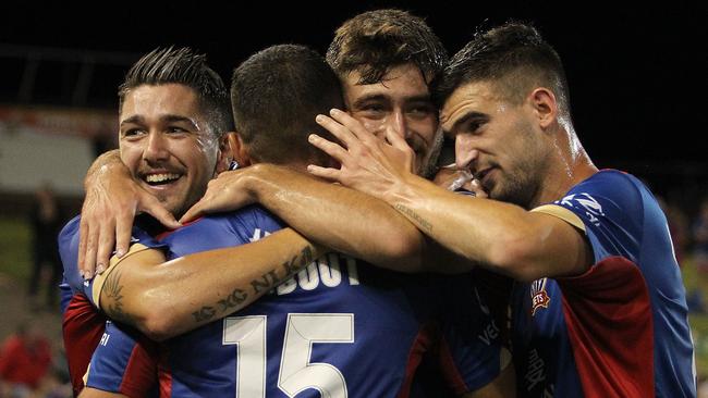 Jets players celebrate a goal against the Melbourne Victory.