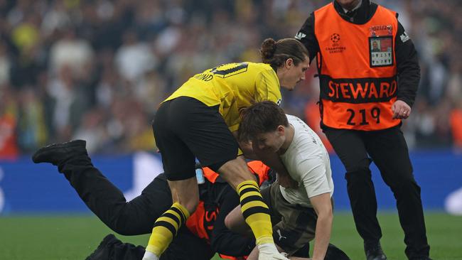 Dortmund's Austrian midfielder Marcel Sabitzer stops a pitch invader. Photo by Adrian DENNIS / AFP.