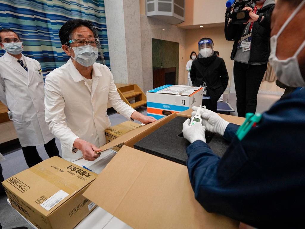 Tokyo hospital staff with delivery personnel inspect a supply of Pfizer vaccines being delivered to a hospital in Tokyo on February 16. Picture: Kimimasa Mayama