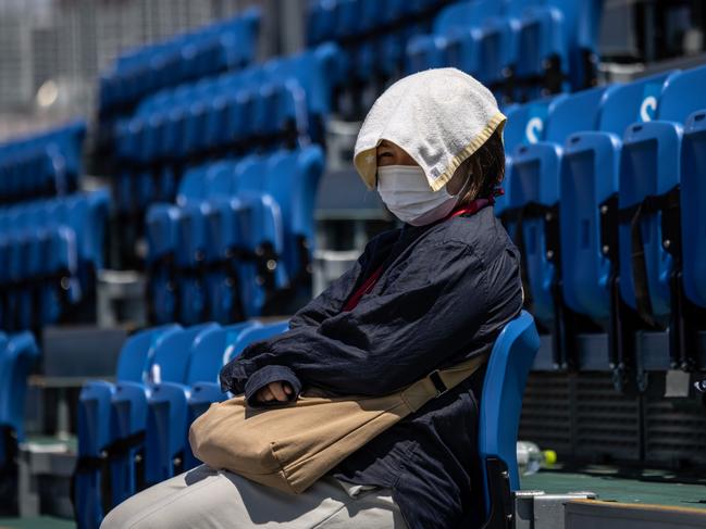 A woman wears a towel on her head to keep cool as she watches a skateboard practice session at Ariake Urban Sports Park on July 22. Picture: Getty Images