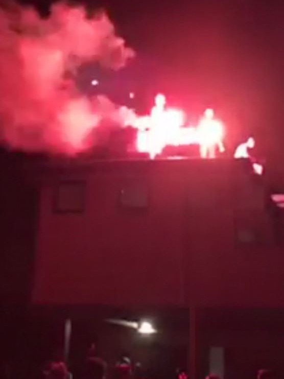 Youths lighting flares on the rooftop of a house in Rye.