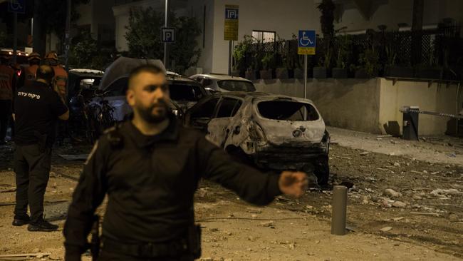 Israeli security forces stand near a burned car at a scene where a rocket fired from Gaza strip hit a building on October 7, 2023 in Tel Aviv, Israel. Picture: Amir Levy/Getty Images)