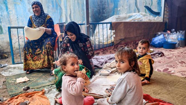 Children sit by a woman preparing traditional unleavened bread on an open fire at school run by the United Nations Relief and Works Agency for Palestine Refugees. Picture: SAID KHATIB