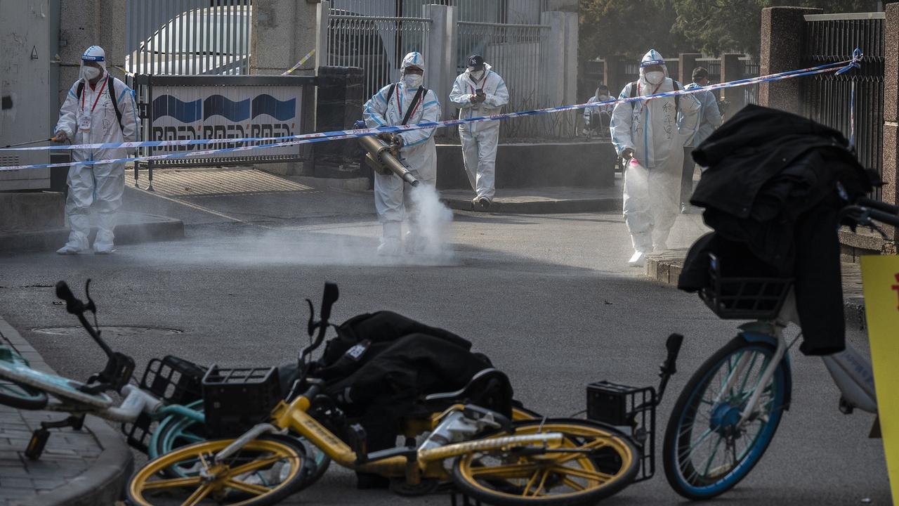 Health workers wear protective suits as they disinfect an area outside a barricaded community in Beijing that was locked down for health monitoring after Covid cases were found. Picture: Kevin Frayer/Getty Images.