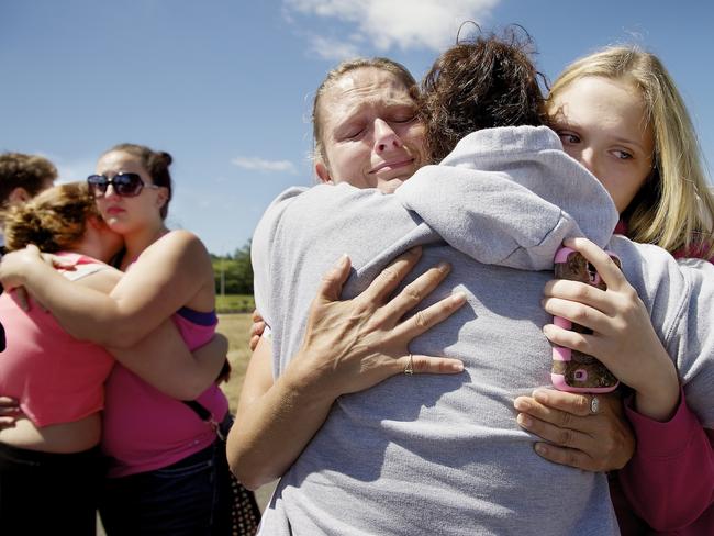 Brandi Wilson, left, and her daughter, Trisha Wilson, 15, right, embrace Trish Hall, a mother waiting for her student, after the Reynolds High School shooting in Oregon. Picture: AP/Troy Wayrynen