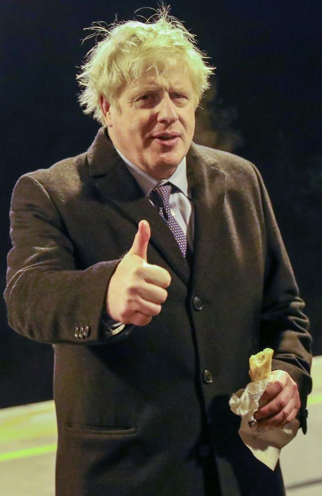 Britain's Prime Minister Boris Johnson eating a sausage roll on a train platform. He wants another five years in government. Picture: Hannah Mckay/AFP