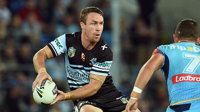 James Maloney of the Cronulla Sharks (left) sidesteps Ash Taylor of the Gold Coast.