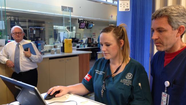 Director of Noarlunga Hospital emergency department Dr Jim Holland with registered nurse Kerrie Searle checking a mobile EPAS screen, with SA Health Chief Medical Officer Professor Paddy Phillips in the background. Picture: Brad Crouch