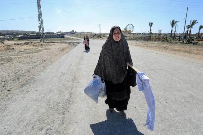 A displaced Palestinian woman carrying a makeshift white flag flees Hamad in Gaza, where Israel has conducted strikes