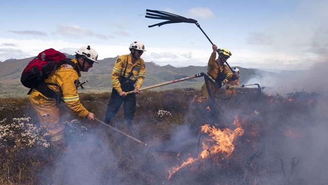 Parks and TFS firefighters smother the remains of the fire edge after aircraft water bombers saturate the area Picture: WARREN FREY/TASMANIA FIRE SERVICE