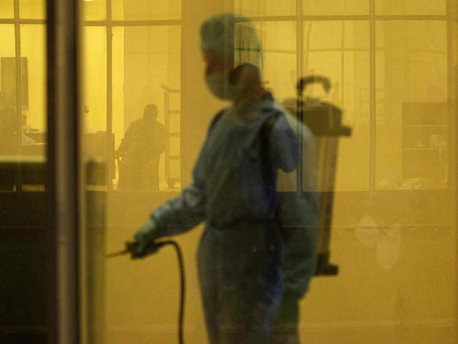 TOPSHOT - A medical staffer wearing full PPE (personal protective equipment) performs a sterilisation at the entrance of an isolated section for COVID-19 coronavirus disease treatment at a hotel in the sports city of Iraq's southern city of Basra on May 11, 2020. (Photo by Hussein FALEH / AFP)