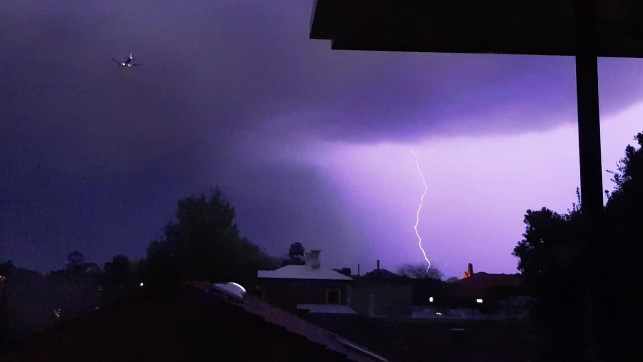 A plane flies in to Adelaide amid a lightning storm. Picture: Kate Jarmyn