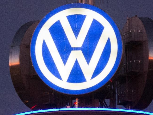 A street sign can be seen in front of the illuminated logo of German car maker Volkswagen (VW) on December 10, 2015 in Hanover, central Germany. Embattled German auto giant Volkswagen is due to provide an update on the latest developments in the massive pollution-cheating storm it has been engulfed in since September. AFP PHOTO / DPA / JULIAN STRATENSCHULTE +++ GERMANY OUT +++