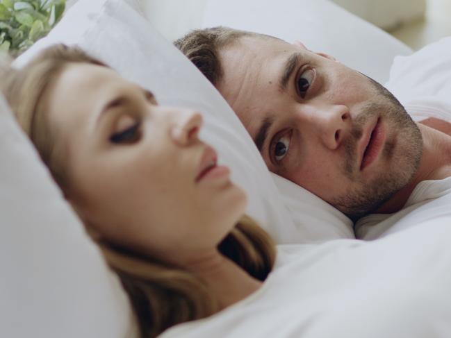 Closeup of couple with relationship problems having emotional conversation while lying in bedroom at home