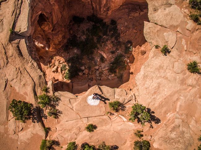 Drone photo of a bride and groom in her wedding dress overlooking a massive Utah desert sinkhole near Moab. Picture: Supplied