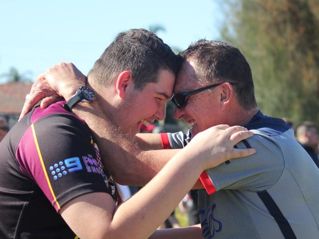 Jake Leyshon hugs his dad Rees Leyshon after his Hills Bulls under 16 team won the title, because he was the last male in the family to win a league grand final.