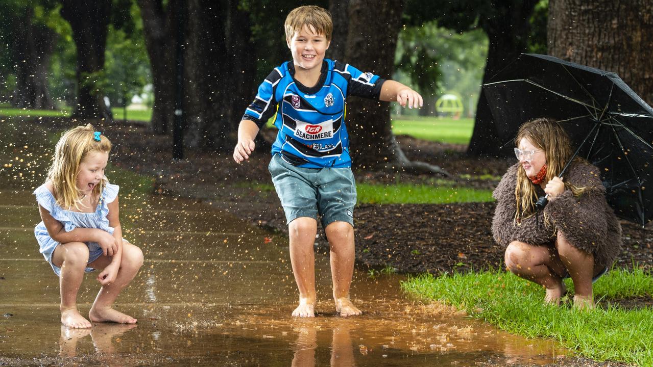 SPLASHDOWN: Winston McBride with his older sister Lola and younger sister Poppy McBride enjoys jumping in puddles in the rain in Toowoomba's Queens Park, Saturday, January 8, 2022. Picture: Kevin Farmer