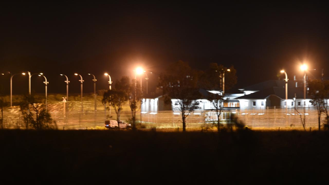 Police vehicles can be seen in the distance at the perimeter of the Capricornia Correctional Centre late during the riots and protests.